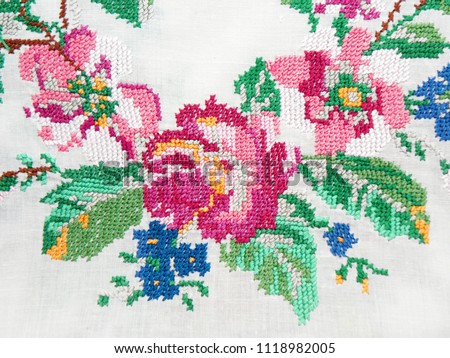 Ukrainian folk embroidery cross-stitch, embroidered red rose flowers isolated on white fabric, fabric decor, hand embroidery