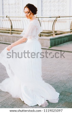 Happy young bride in flowing white dress enjoying herself outdoors