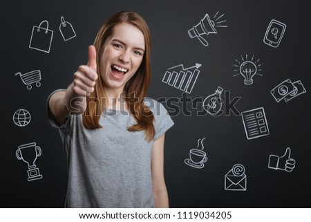 Optimistic person. Positive clever student putting her thumb up and feeling excited while trying to find and interesting job