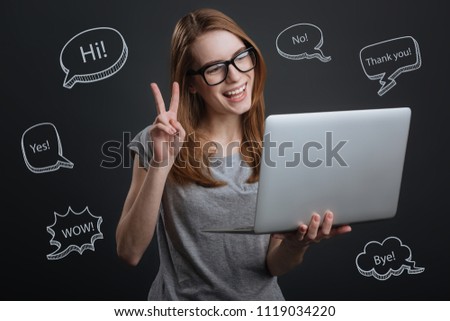 Video call. Positive friendly young woman feeling happy and holding a modern laptop while having a pleasant video call
