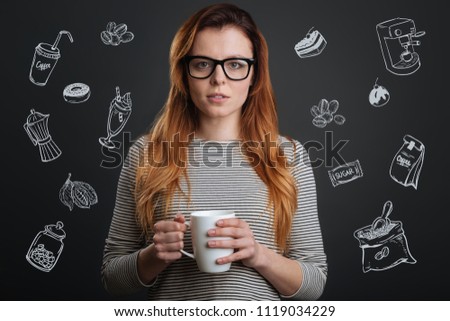 Drinking coffee. Sleepy young woman standing alone with a cup of coffee in her hands and looking sleepy