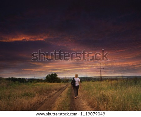 hiking on the country road . Rural road . Happy woman  .  the woman going to a decline . foot walk with a backpack . Tourist girl enjoying view . 