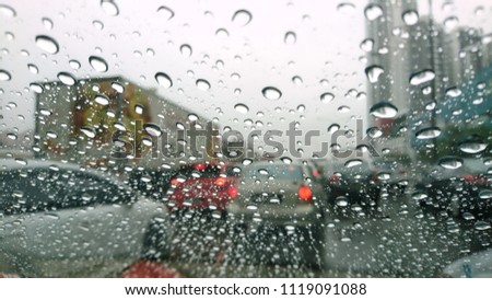 Blured background with rains drop on glass and cars on the road. Rain on the street, in the city. Raindrops falling on a glass droplets. 