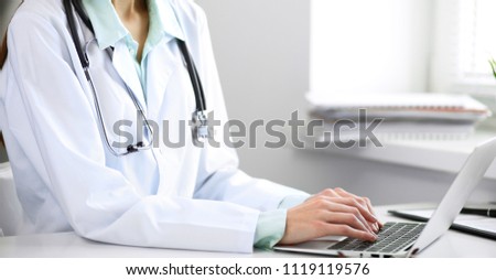 Close up of  unknown female doctor sitting  at the table near the window in hospital