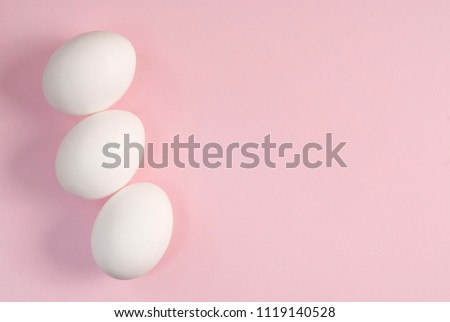 Three white eggs on a pink background