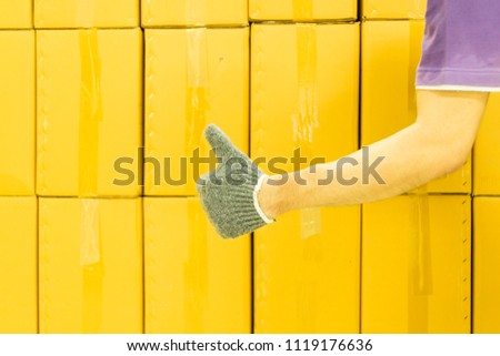 Close-up of man hand with thumb up in front of cardboard boxes, likes or approves concept.