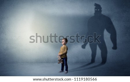 Cute kid in a room with plush on his hand and hero shadow on his background