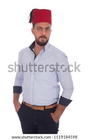 young handsome man putting hands in pockets and wearing tarboosh , isolated in white background Royalty-Free Stock Photo #1119184598