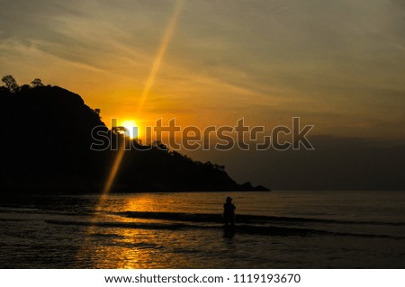 Fisherman silhouette, sunrise and mountain background at Hua-Hin beach Thailand