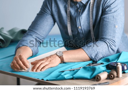 Tailor working at table in atelier, closeup
