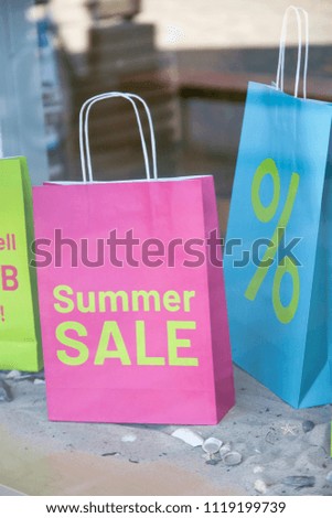 
Paper shopping bags in the window shop, summer sale offer concept, touristic agency or shopping mall