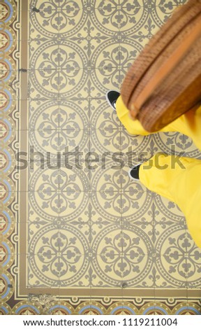Fashion photo selfie of feet. Sneaker shoes and yellow trausers on art pattern moroccan style tiles floor, top view