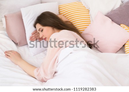 A sweet girl sleeps in bed in light bedroom in the morning.