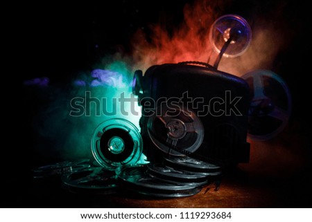 Old style movie projector, still-life, close-up. Film projector on a wooden background with dramatic lighting and selective focus. Movies and entertainment concept