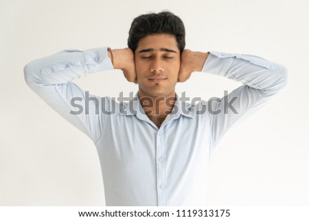 Calm Indian guy tired of arguing, noise, loud sounds. Portrait of attractive young man covering ears with hands. Do not want to hear concept