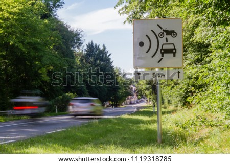 Speed limit speed camera sign with cars driving too fast