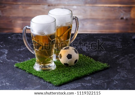 Picture of two glasses of beer, soccer ball on green grass