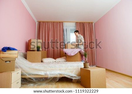 Photo of man with cardboard boxes in bedroom.