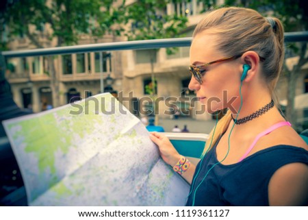 Pretty girl enjoying bus tour in Europe, exploring map and listening stories about famous places of Barcelona, happy active summer vacation, Spain
