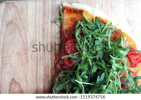 Italian pizza with rocket salad and cherry tomatoes
