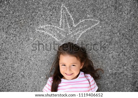 Cute little girl lying on asphalt, outdoors