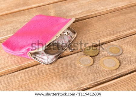Wallet with coins on a wooden table . On wooden background .