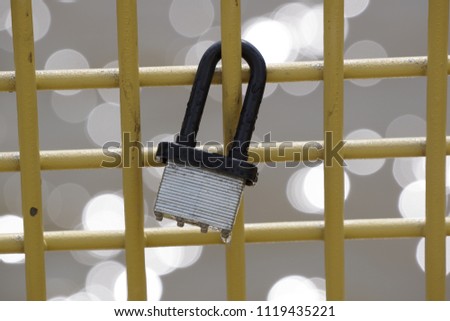 Love padlock on yellow bridge fence with blurry water background
