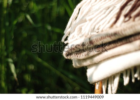Folded woolen blanket in a close up on a background of a green garden.