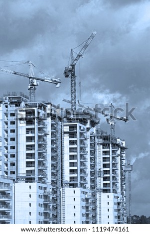 Construction work of high-rise residential buildings.Active construction of the housing complex, with the working cranes .Blue Toned Image

