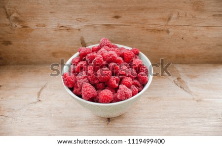 Fresh berries raspberry ripe heap pile in blue green mint сup plate dish on country retro vintage table made of solid wood top veiw natural summer day light