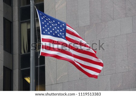 Flag of USA waving in the wind with gray color business highrise building background