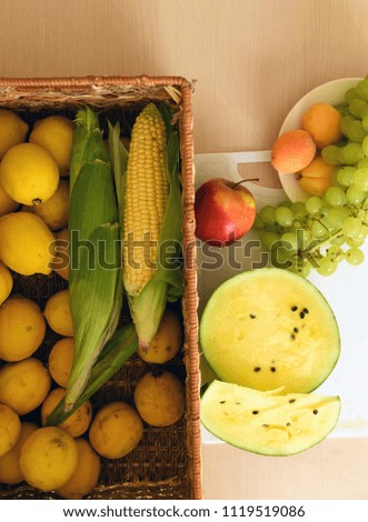 Corns,apple,yellow watermelon,peaches,grapes and lemons in a straw basket, vegetables, kitchen, vegetarian, plant based