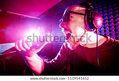 The singer sings with a microphone in the recording studio. Modern background