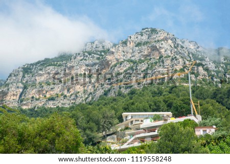 Construction of a house and a construction crane in the mountains