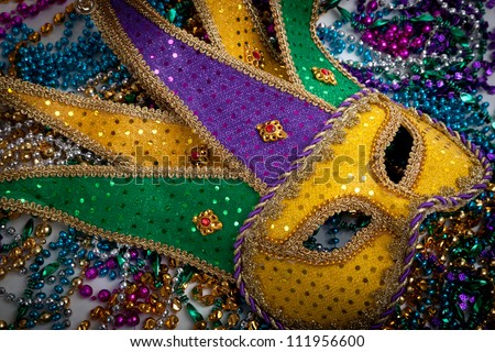 A yellow Mardi Gras jester mask and beads