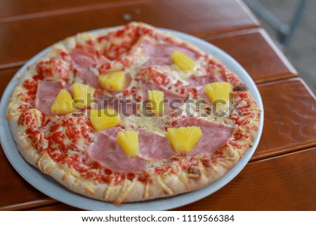 Hawaiian pizza with pineapple and ham slice on white dish