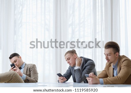 technology addiction. business men using their phones at office meeting. idle life and work style.