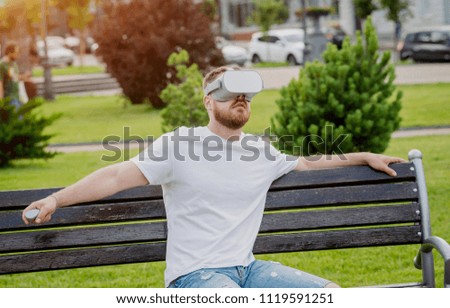 A young man plays a game wearing virtual reality glasses on the street. VR headset