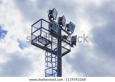 Lighting mast on a background of a cloudy sky, light for playing on a football field