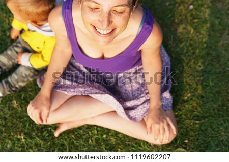 a peaceful smiling mom with her son in the park with green background on a sunny summer day