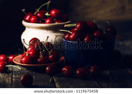 still life picture in the dark of fresh cherry on plate on wooden black background. fresh ripe cherries. soft focus image