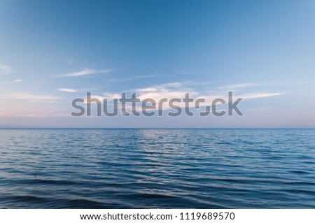 Clouds over blue sea waves. Sky reflecting in water. Ladoga lake.