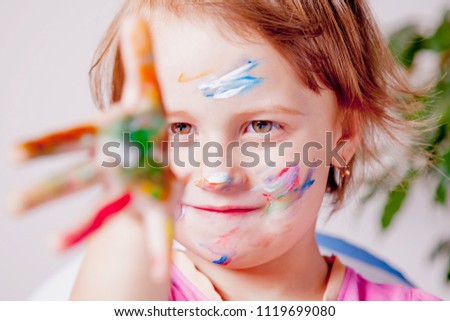 Art, creative and happiness concept. Colorful painted hands and face in a beautiful young girl. 