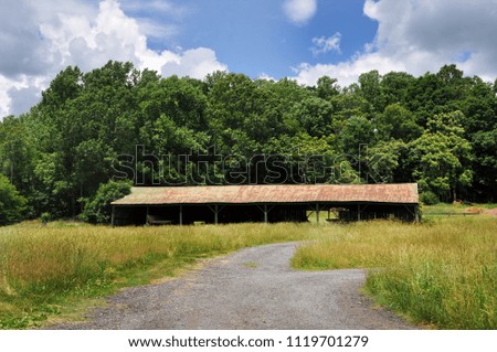 A green barn in a field in a rural area of Virginia.