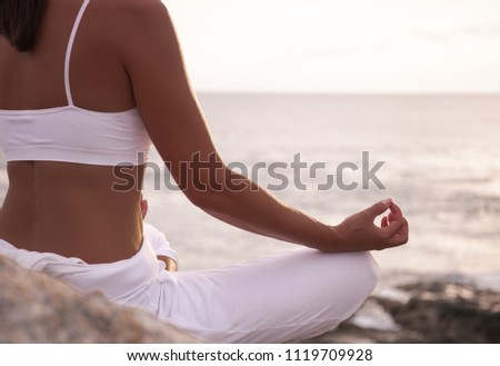 Woman meditating in a yoga pose on the beach