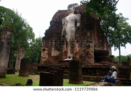 Travelers thai woman walking visit and travel take photo in ancient building and ruins of Kamphaeng Phet Historical Park is an archeological site and Aranyik Area in Kamphaeng Phet, Thailand