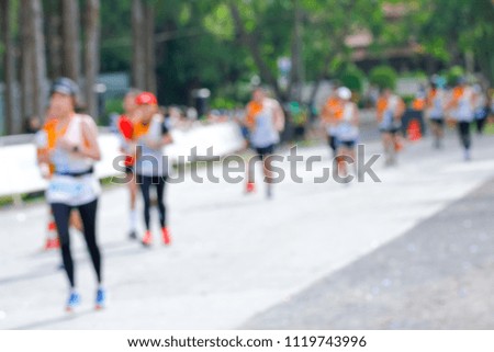 Motion blur image of a large group of runners running on a road.