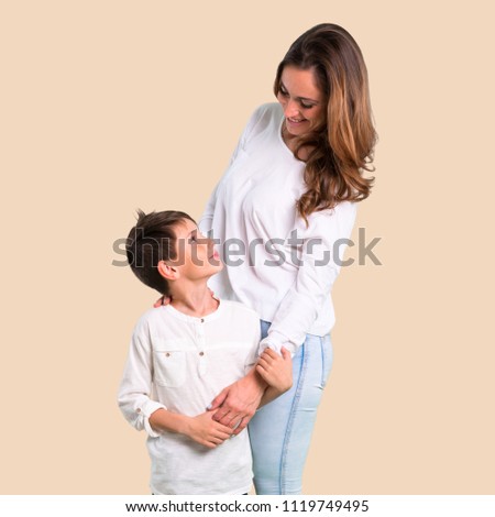 Mother and son laughing on ocher background