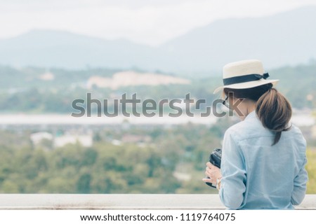 Back side of young Asian traveling woman looking and taking photos of beautiful landscape of Northern Thailand, traveller and tourist concept.