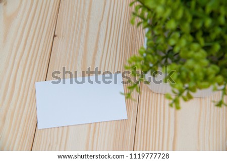 Blank business cards and little decorative tree in white vase on wooden working table with copy space for add text ID. and logo, business company concept idea.